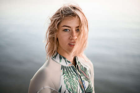 portrait of young beautiful blonde woman with wet hair in gray wetsuitの写真素材