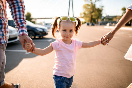 Little smiling blonde girl walks with parentsの写真素材