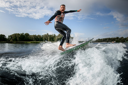 man black swimsuit rides a wave off the coast with his surfboard.