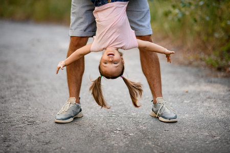 close-up of the face of little girl which her father hold upside down