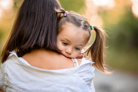 rear view of woman who holds in her arms little girl with ponytails
