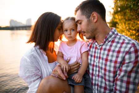 Lovely family portrait of mother and father and little cute daughter on summer day.の写真素材