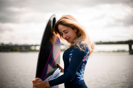 beautiful woman with closed eyes holds surfboard and rests head on itの写真素材