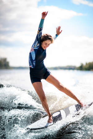 Close-up of young woman elegantly balances on surfboard riding the wave.の写真素材