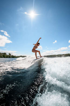 attractive woman on surfboard rides up the wave against the background of the bridgeの写真素材