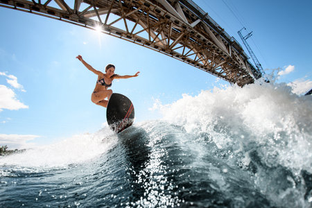 handsome woman skillfully bounces on the wave with surfboard