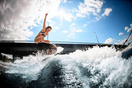 young woman skillfully bounces on the wave with surfboardの写真素材