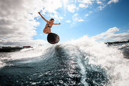 smiling woman skillfully bounces on the wave with surfboardの写真素材