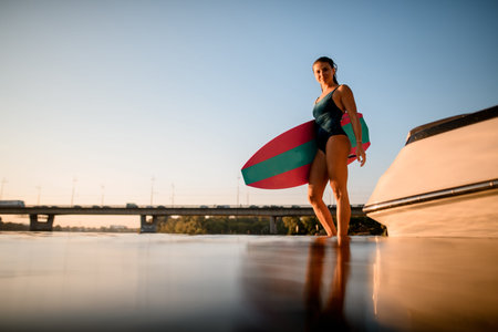 beautiful young woman in swimsuit with surf style wakeboard standing in the water.