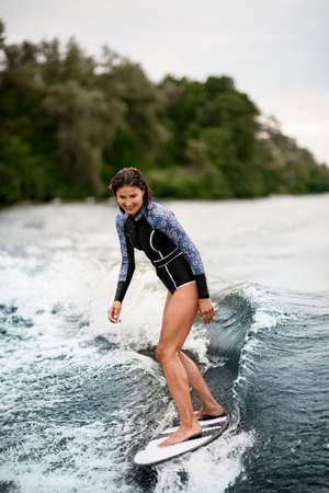 handsome smiling woman stands on a surfboard and rides the waveの写真素材