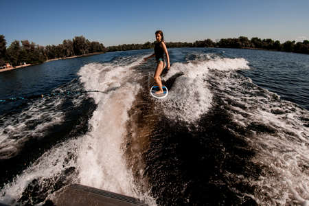 high angle view of young woman wakesurfer rides the wave from the boatの写真素材