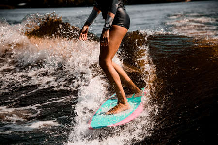 view on tanned legs of woman riding wave on surf style wakeboardの写真素材