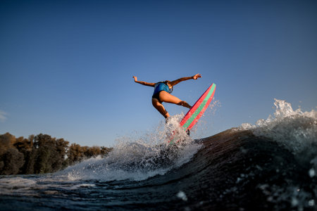 attractive sexy woman jumping on big splashing wave on surf style wakeboard.