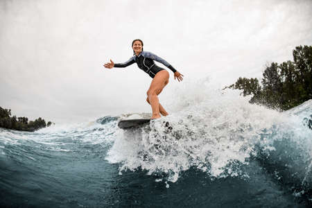 handsome woman stands on a surfboard and professionally rides on the waveの写真素材