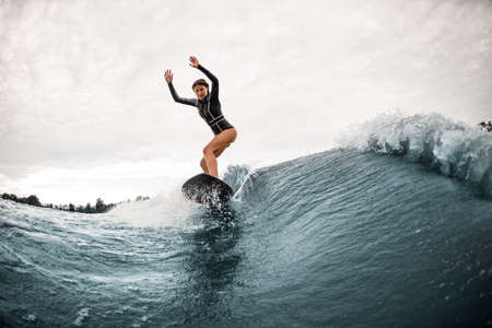 young woman stands on a surfboard and actively rides on the waveの写真素材