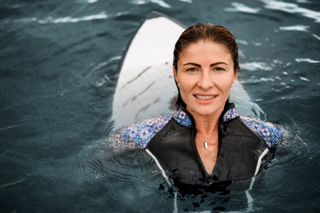 portrait of woman with wet brown hair in water with wake surf board