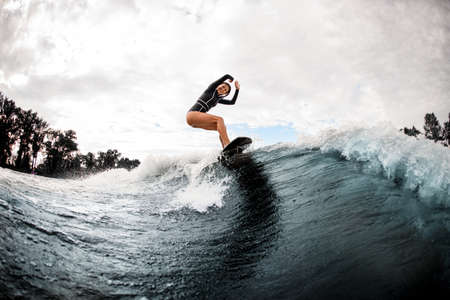 happy smiling woman riding the wave on surfboard on warm summer dayの写真素材