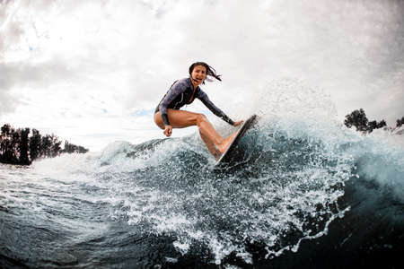 woman in swimsuit engaged in extreme sport and rides board on river waveの写真素材