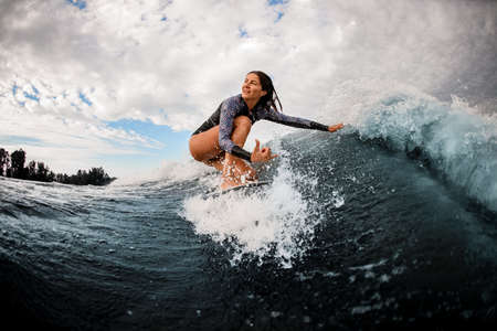 woman riding on wave sitting on surf board and touching the water with her hand.の写真素材