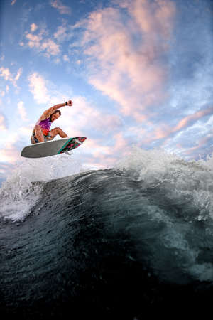 view of sports guy riding wave doing jumps and tricks on the surf style wakeboardの写真素材