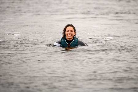 view of young smiling woman in wetsuit with vest in the water.の写真素材