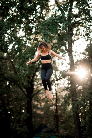 happy woman bouncing on trampoline and performs trick in the air
