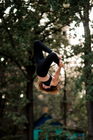 view of woman skillfully jumps and performs trick upside down in the air