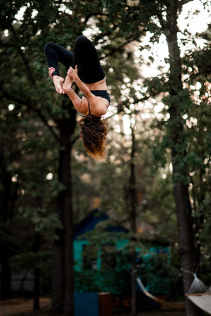 view of young woman skillfully jumps and performs trick upside down in the air