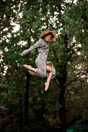 active young woman with bend knees jumps high in the air