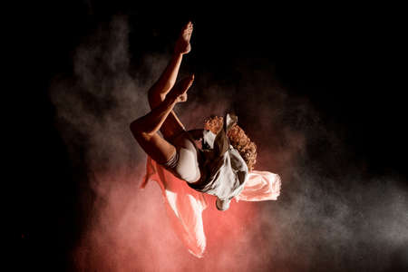 view of woman perfectly jumps and performs trick upside down in the air at darkの写真素材