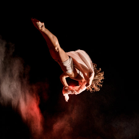Beautiful young female athlete flying upside down outdoor at dark time