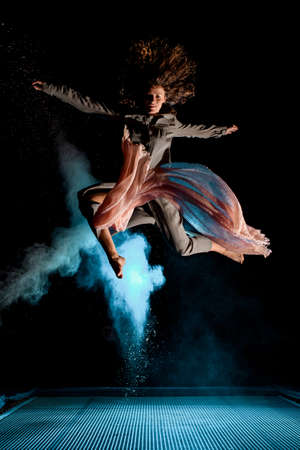 Beautiful woman effectively jump high in the air at dark timeの写真素材