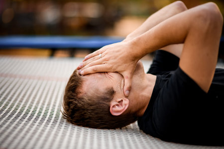 Close-up view of young man in black clothes lying on trampoline.