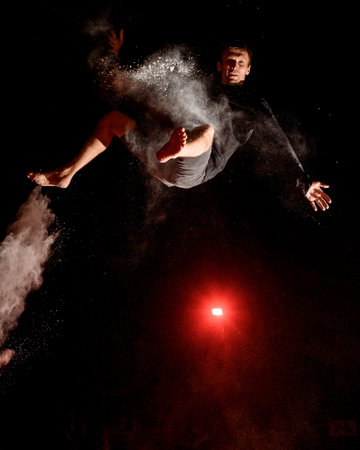 Young man jump high in the air and light of searchlight illuminates him