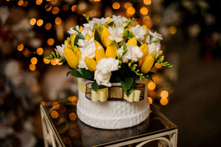 Gorgeous arrangement of fresh flowers in white ceramic pot decorated with ribbonの写真素材