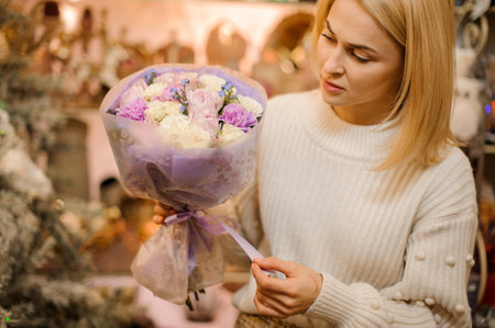 blonde woman florist neatly ties in ribbon on delicate bouquet of fresh flowers.の写真素材