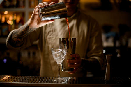 Bartender pouring cocktail from one glass into another glass.の写真素材