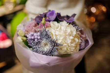 close-up of beautiful floral bouquet with purple flowers and white hydrangea wrapped in paperの写真素材