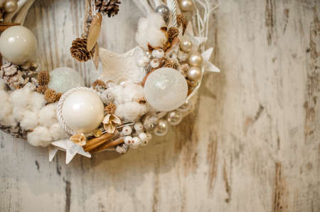 close-up of Christmas wreath decorated with white balls, pine cones, cinnamon sticks and cotton flowers.の写真素材
