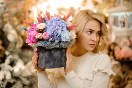blonde woman holds composition with flowers of hydrangea rose and peony in her hands.の写真素材