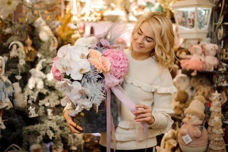 woman holding large floral arrangement of orchids and hydrangeas and roses in box with ribbonの写真素材