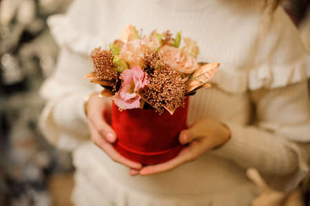 small composition of roses decorated with gilded twigs in red box in womans handsの写真素材