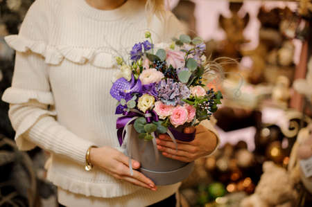 magnificent arrangement of white and purple flowers in round box in hands of womanの写真素材