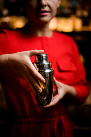 close-up view of polished steel shaker in hands of woman in red dressの写真素材