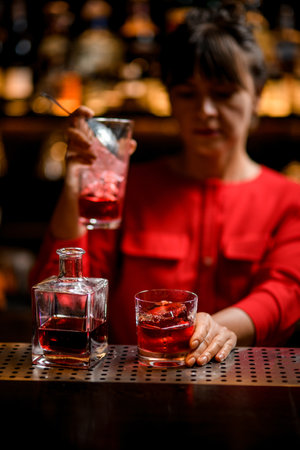glass with big piece of ice and bottle of drink stands on bar counterの写真素材