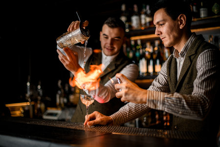 View of bartender man who sets on fire cocktail glass at barの写真素材