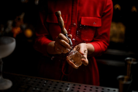 close-up of hands of woman bartender who splits ice cube with tool