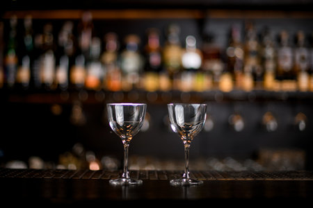 two beautiful transparent glasses with liquid stands on the bar counter.の写真素材