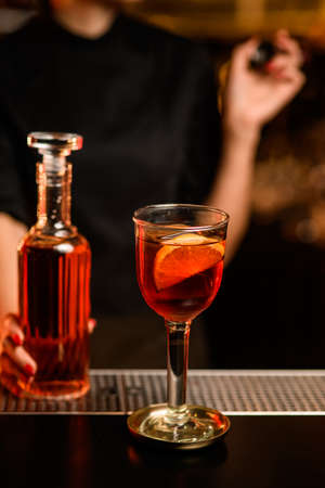Close-up of glass with cocktail on bar and bottle with drink in hand of bartender nearbyの写真素材