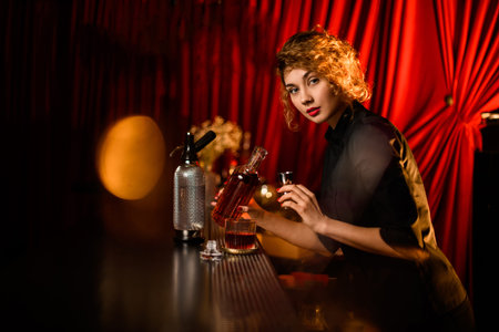 young beautiful woman at the bar prepares cocktail and looks at the camera